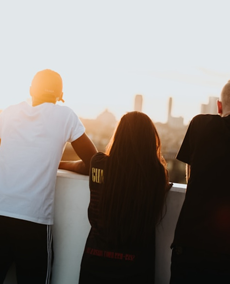 Three young people enjoying the sunset from their apartment balcony