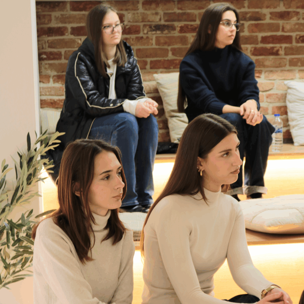 Two girls listening carefully to Jeta Zagragja's talk during the visit at AnchorzUp